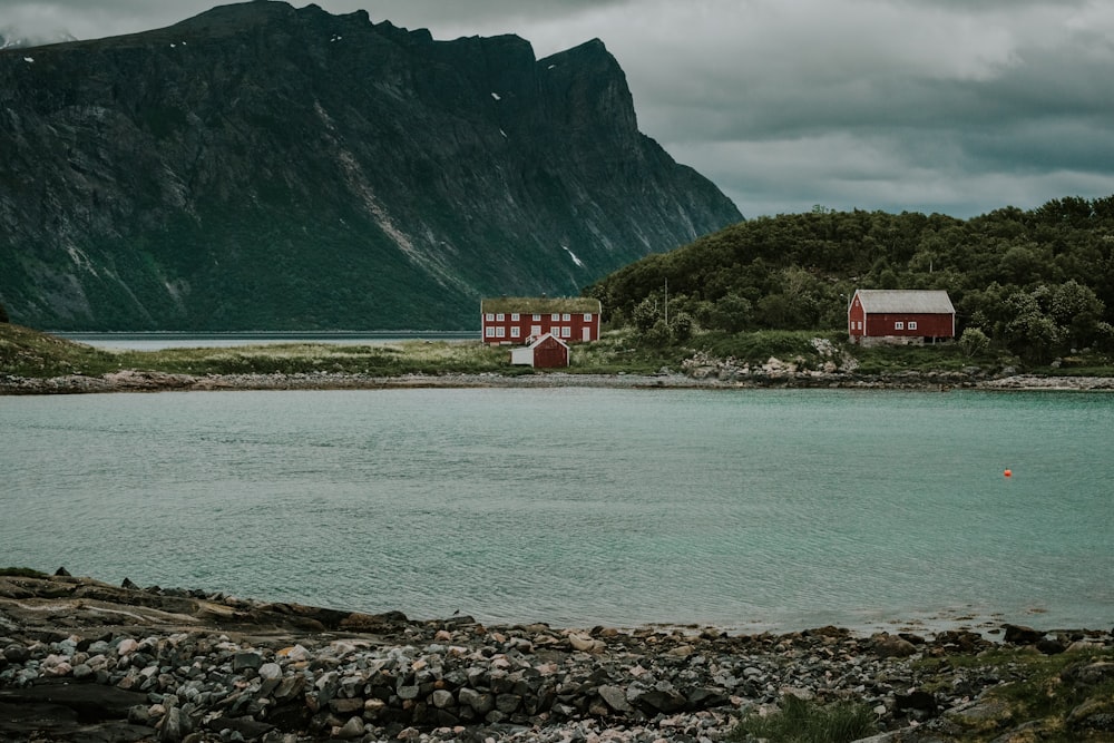 red and white house near body of water and mountain