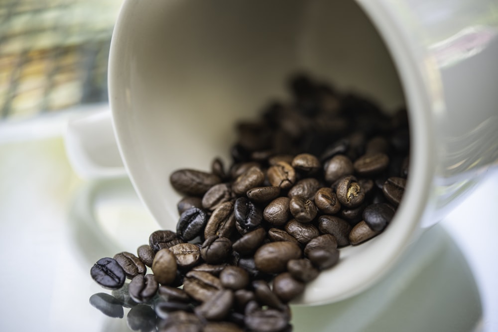 Granos de café marrones en taza de cerámica blanca