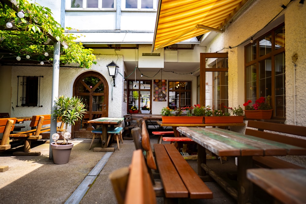 a patio with wooden benches and potted plants