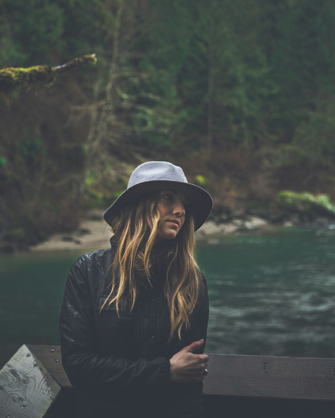 woman in black jacket and white hat sitting on wooden dock during daytime