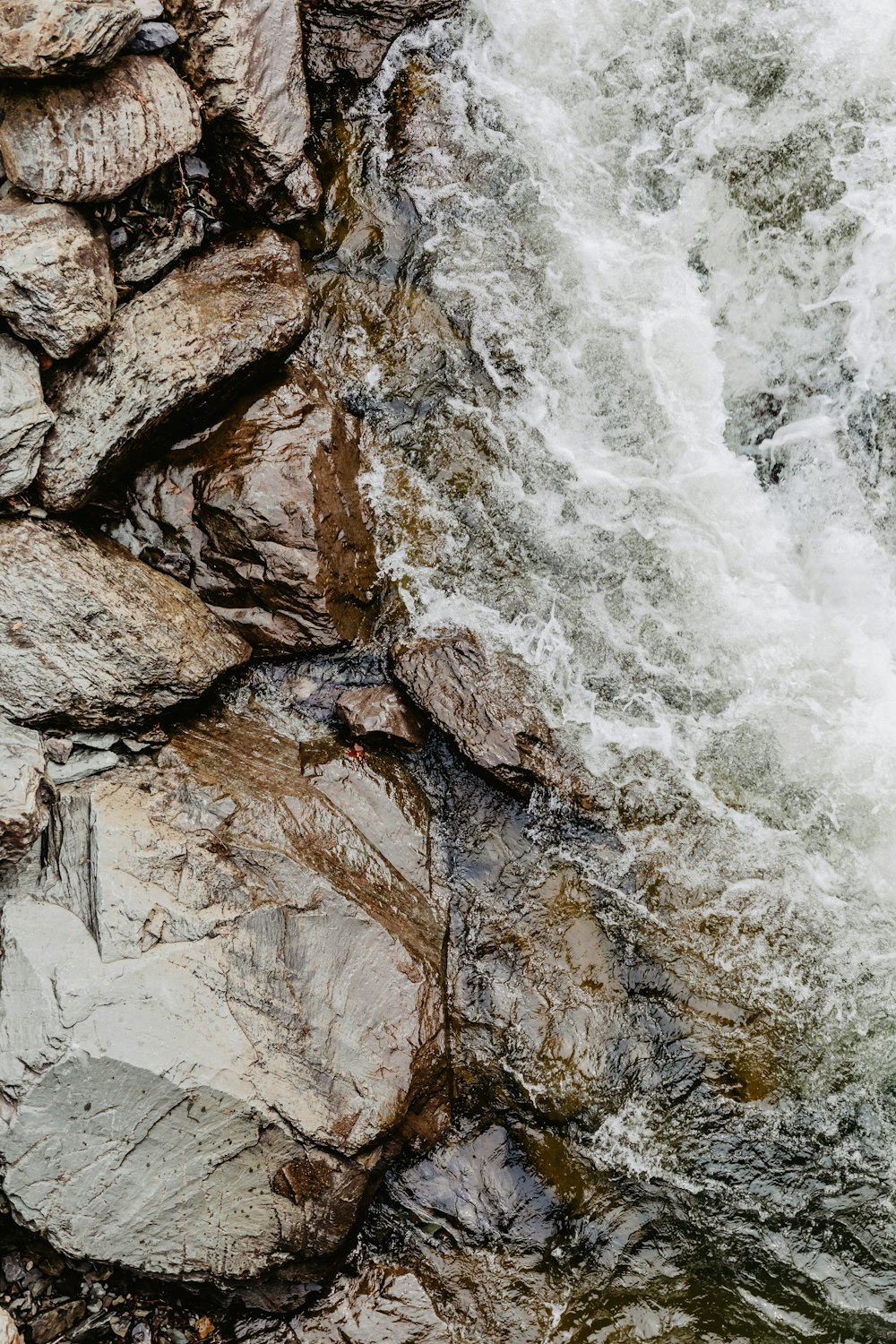 water falls on rocky shore during daytime