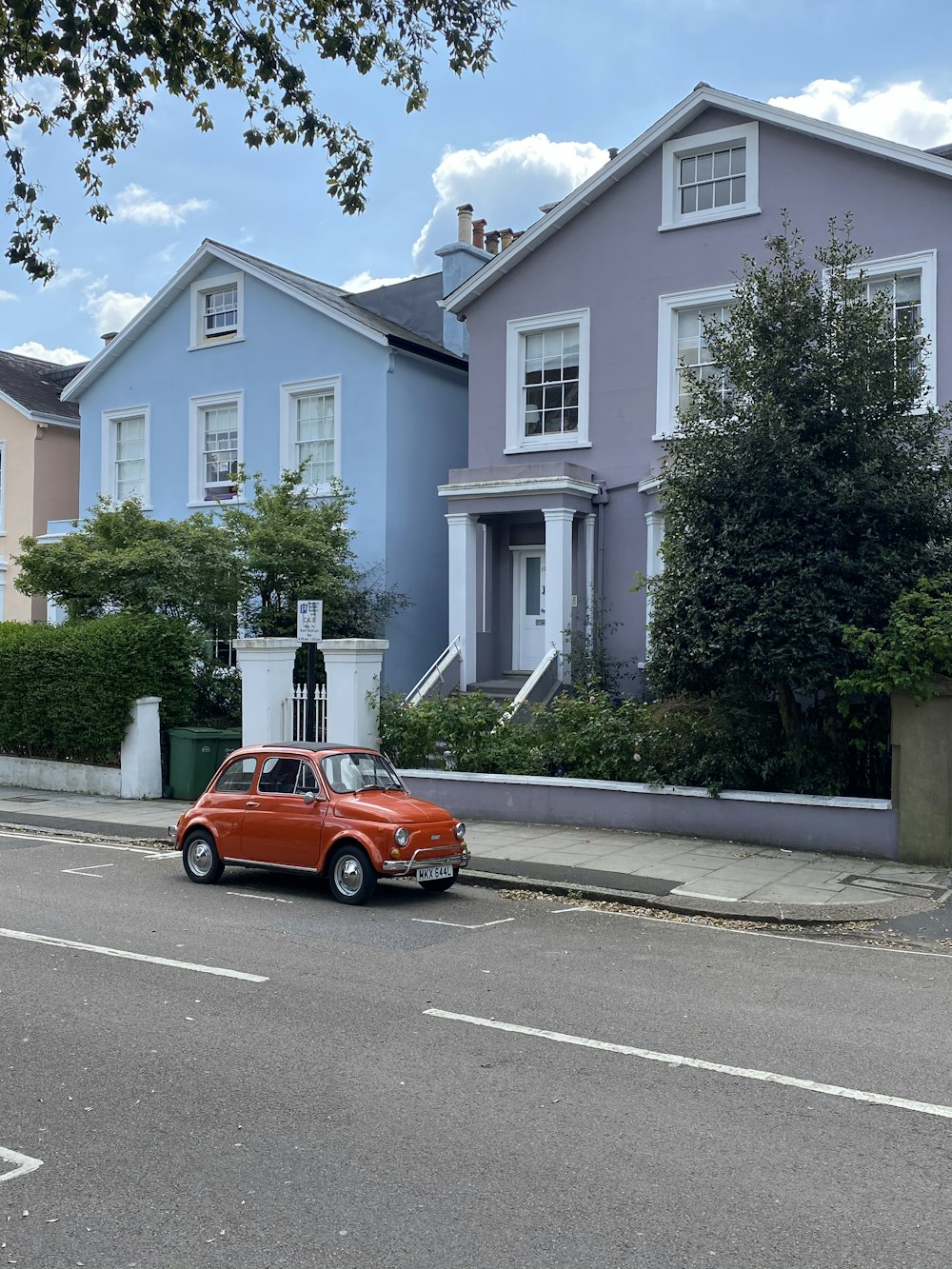 orange car parked near green tree during daytime