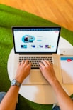 person using macbook pro on white table