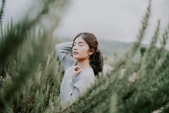 A serene person practicing deep breathing surrounded by soft natural light and greenery.