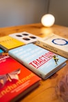 A collection of business and strategy books is displayed on a wooden surface. The books have titles related to customer growth and gamification. A warm light glows in the background, giving the scene a cozy, intellectual ambiance.