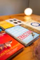 A collection of business and strategy books is displayed on a wooden surface. The books have titles related to customer growth and gamification. A warm light glows in the background, giving the scene a cozy, intellectual ambiance.