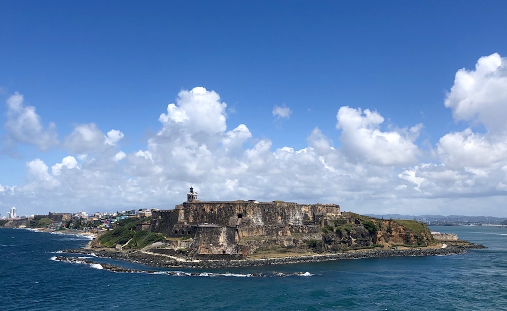 pessoas em pé em formação rochosa perto do mar sob o céu azul durante o dia