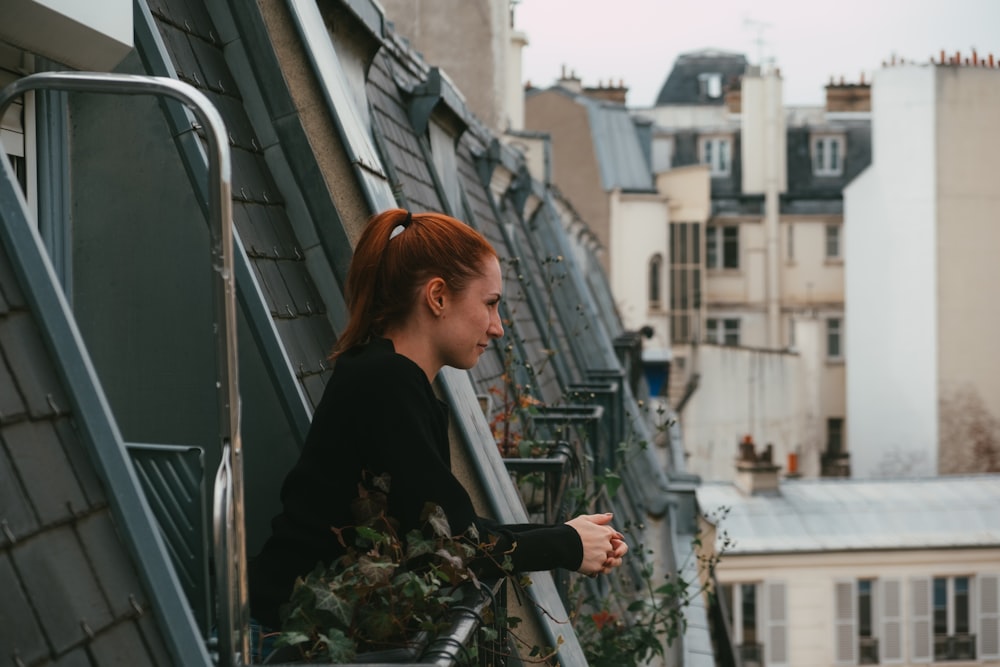 woman in black long sleeve shirt standing beside gray metal railings during daytime