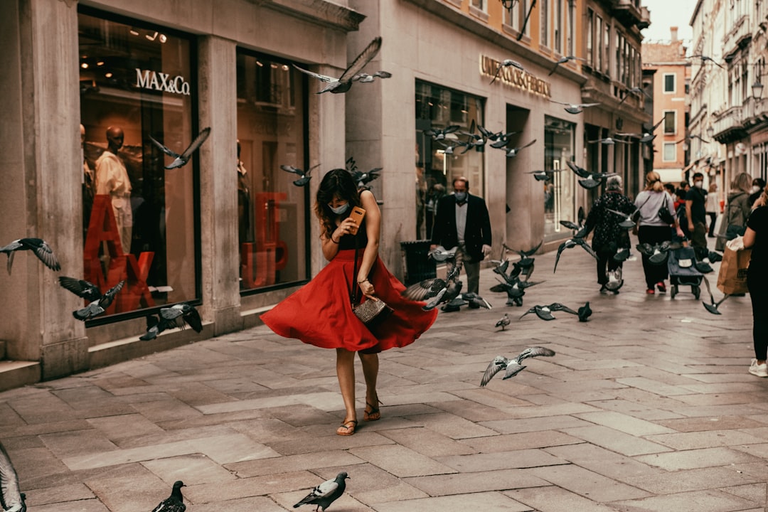 woman in red dress sitting on sidewalk during daytime