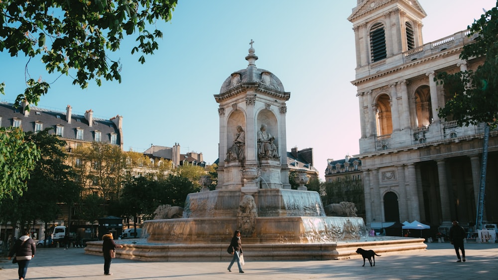 people walking on park with fountain in front of white concrete building during daytime