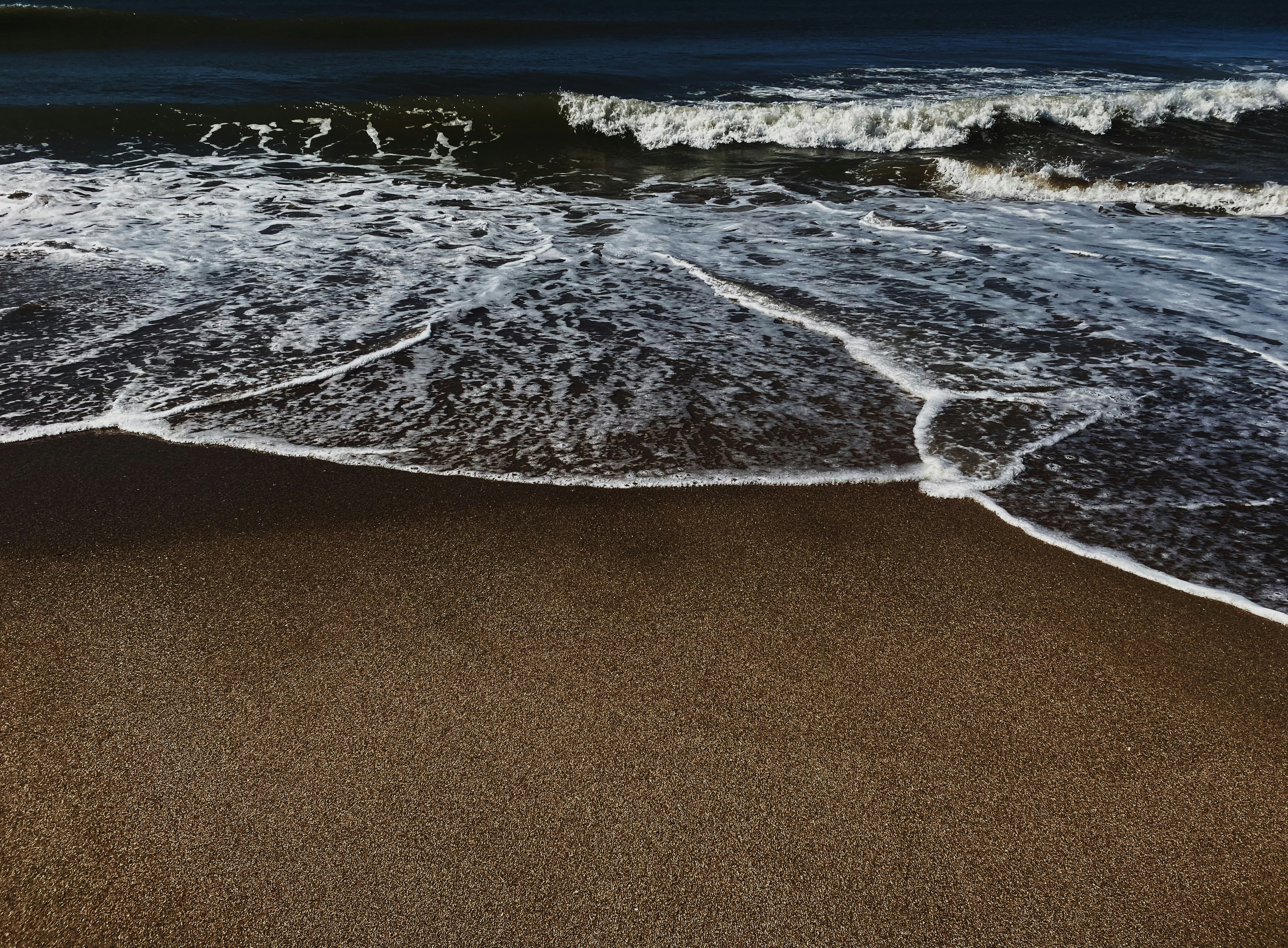 sea waves on brown sand during daytime