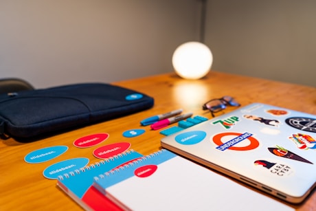 Brand identity elements including stickers, notebooks, and a laptop with custom branding.