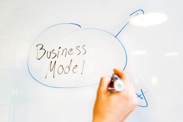 Hand writing 'Business Model' on a whiteboard