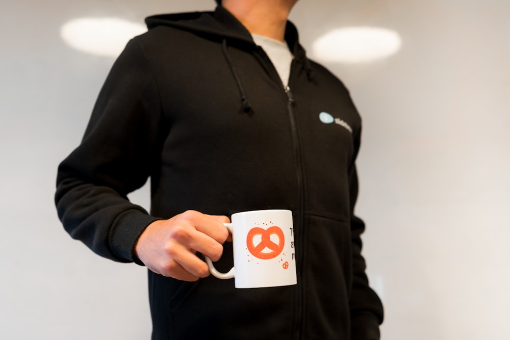 man in black zip up jacket holding white and orange card