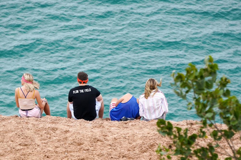 man in black crew neck t-shirt sitting on brown rock beside woman in blue t