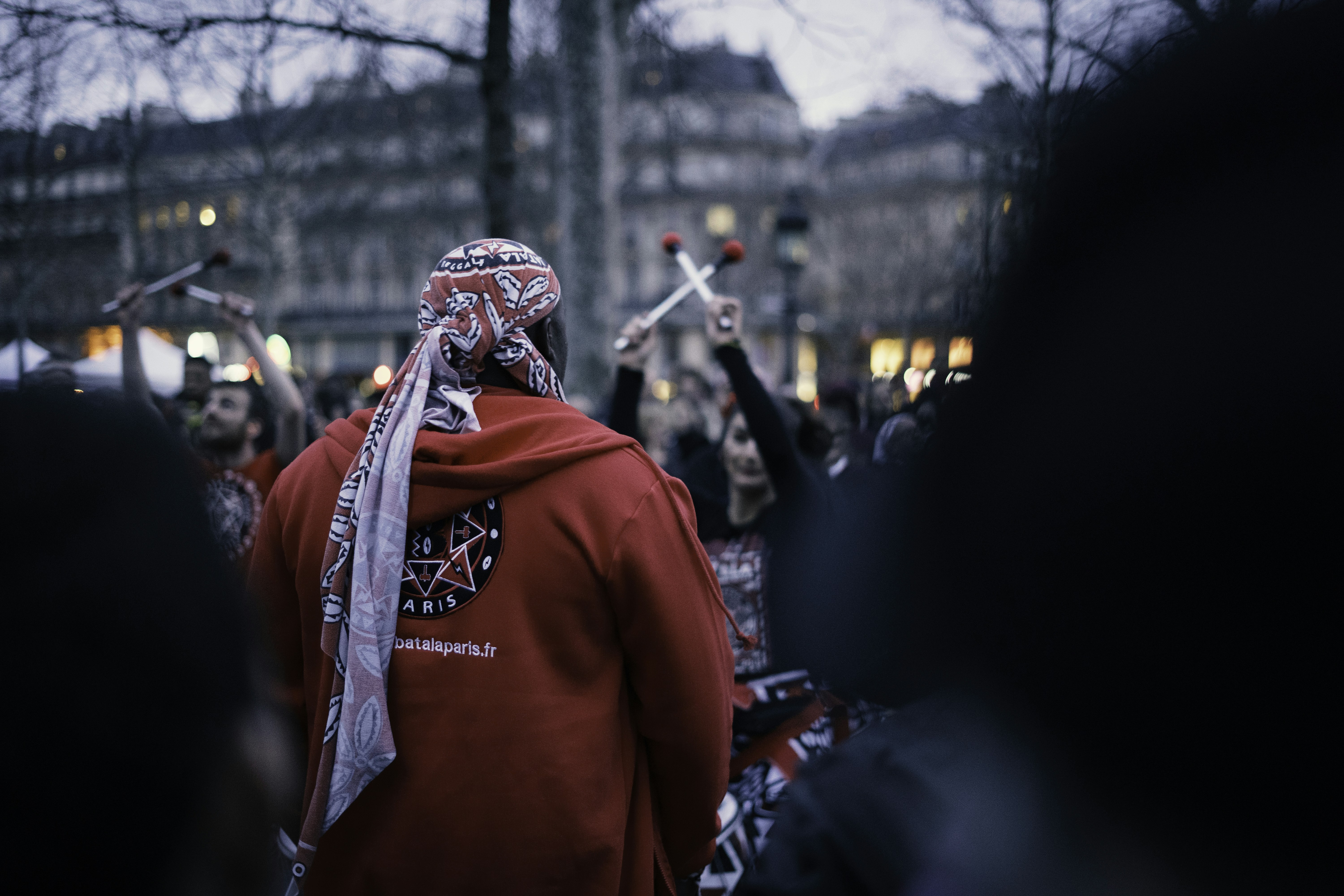 man in red hoodie wearing mask pageant teams background
