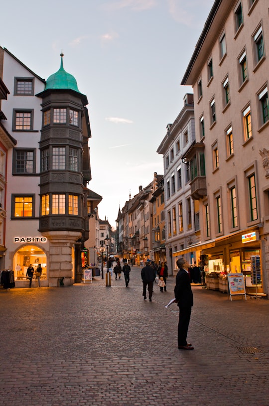 people walking on street near brown concrete building during daytime in Schaffhausen Switzerland