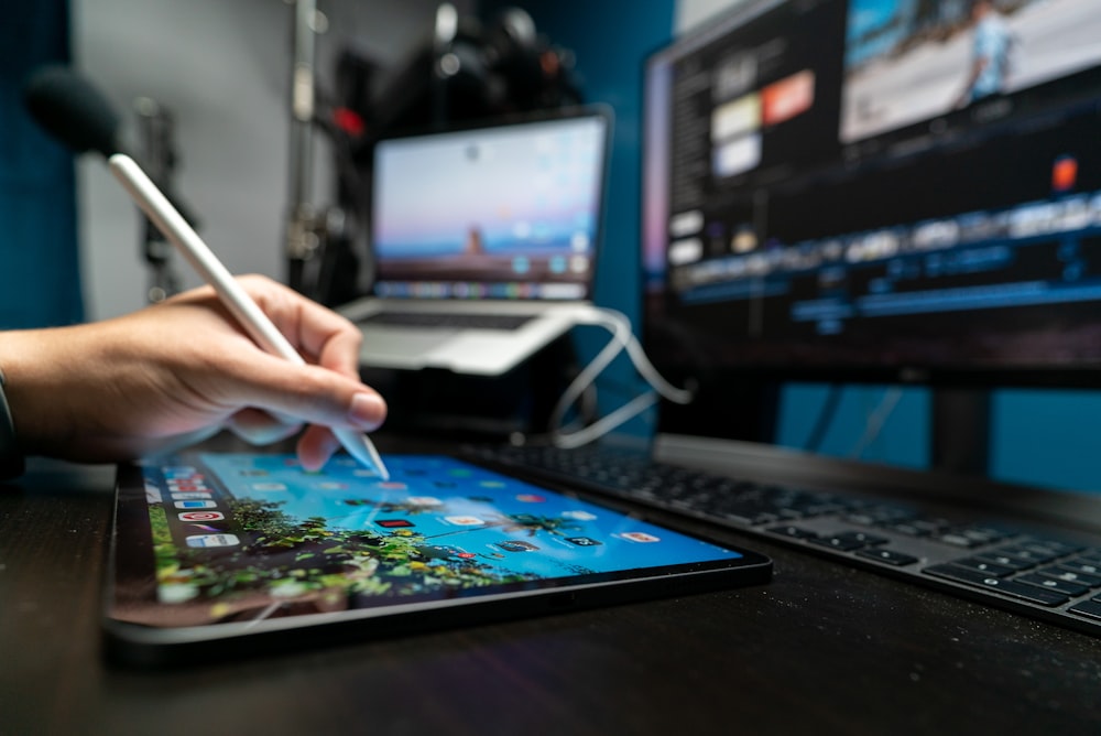 person holding pen in front of black laptop computer