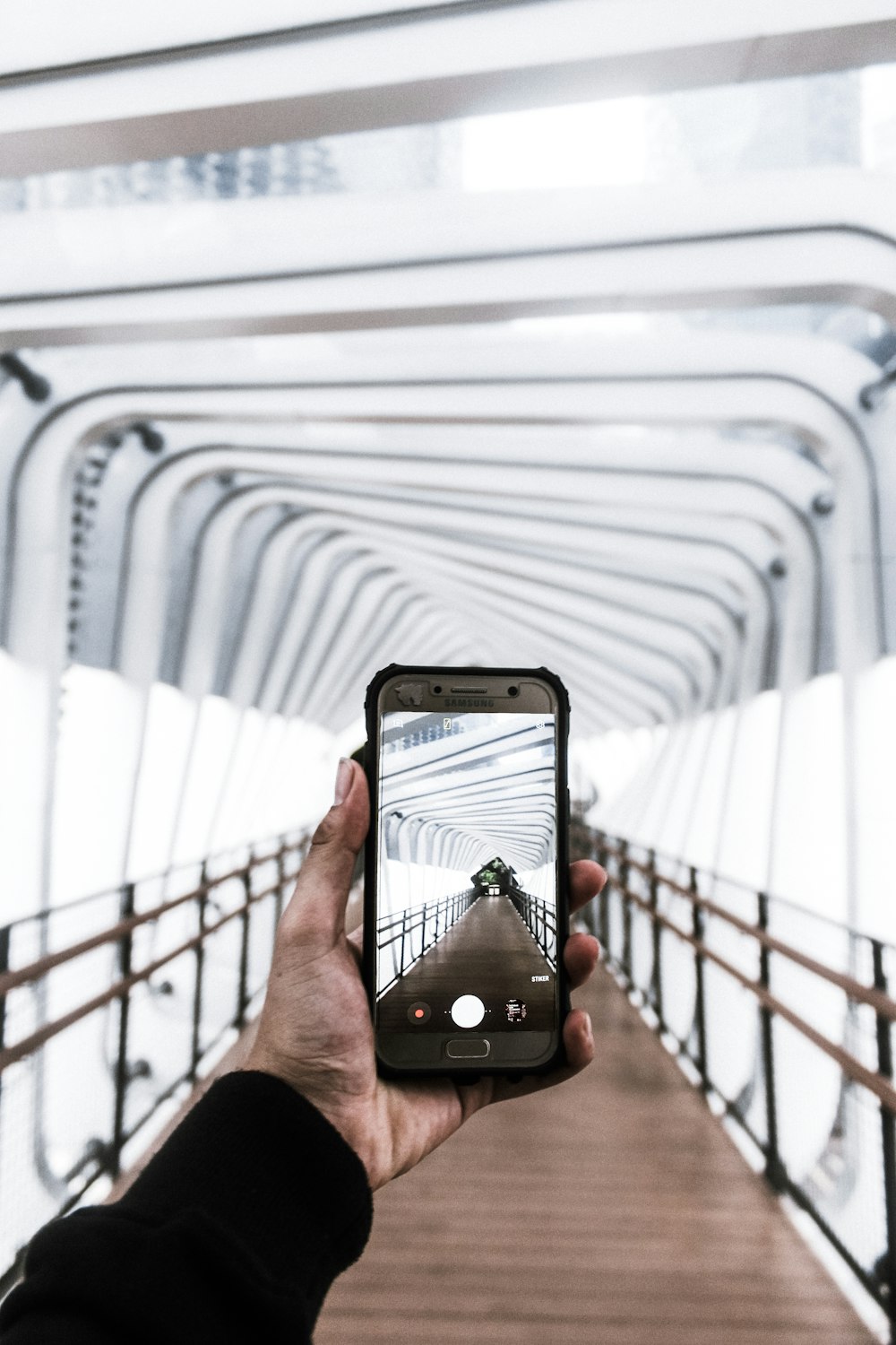 person taking photo of white metal fence