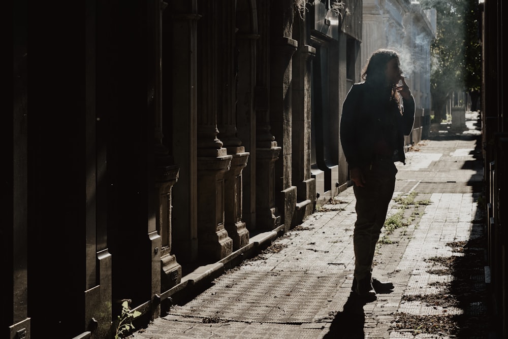 man in black coat walking on sidewalk during daytime