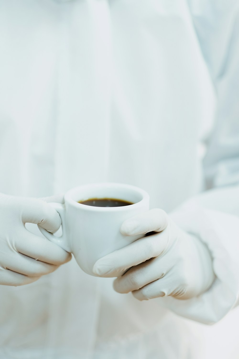 person holding white ceramic mug with brown liquid