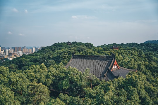 brown and white house surrounded by green trees under white clouds during daytime in Hangzhou China