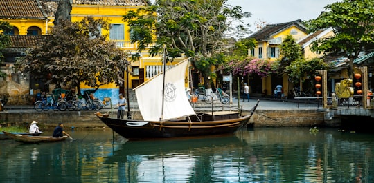 brown and white boat on water near brown building during daytime in Hoi An Vietnam