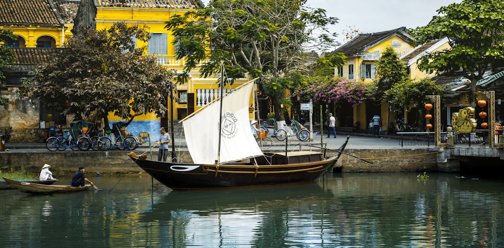 barco marrom e branco na água perto do edifício marrom durante o dia