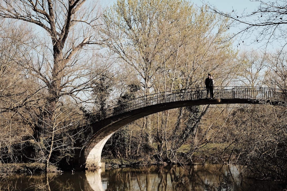 man in black jacket and pants standing on bridge over river during daytime