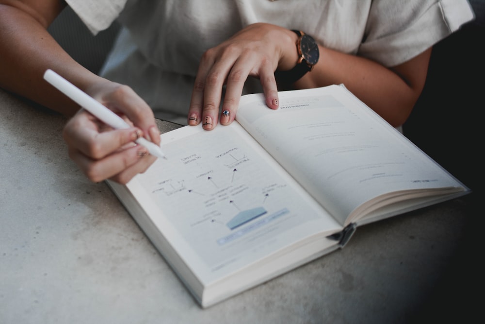 person holding pen writing on white paper