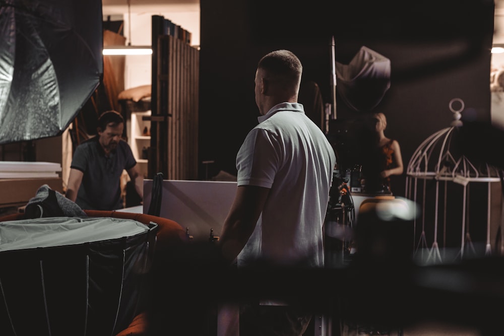 man in white crew neck t-shirt standing near table