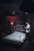 man in white t-shirt standing beside bed
