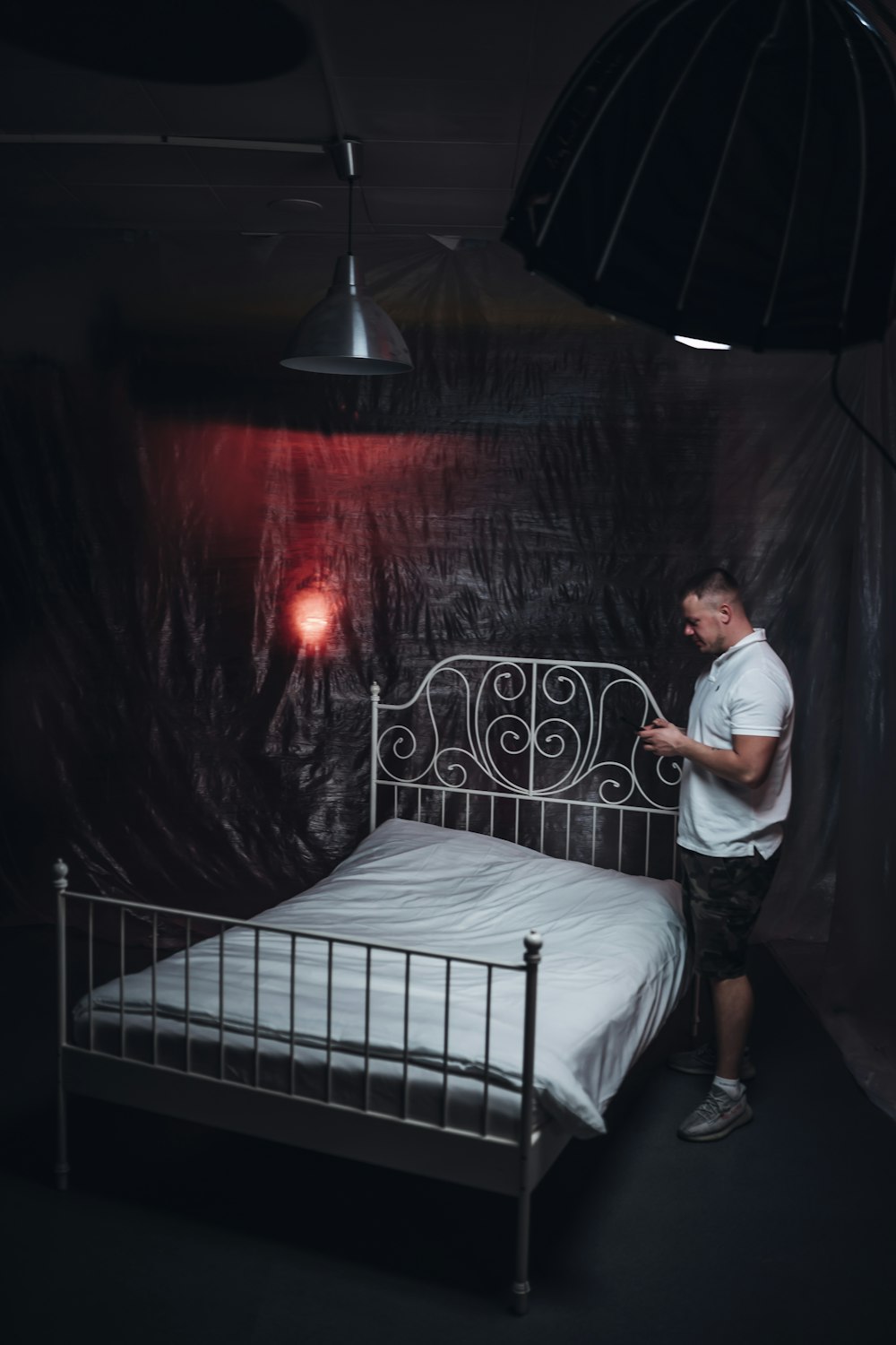 man in white t-shirt standing beside bed