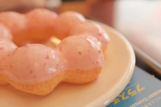 Close-up of a vibrant pink frosted vegan donut with sprinkles on a rustic wooden table
