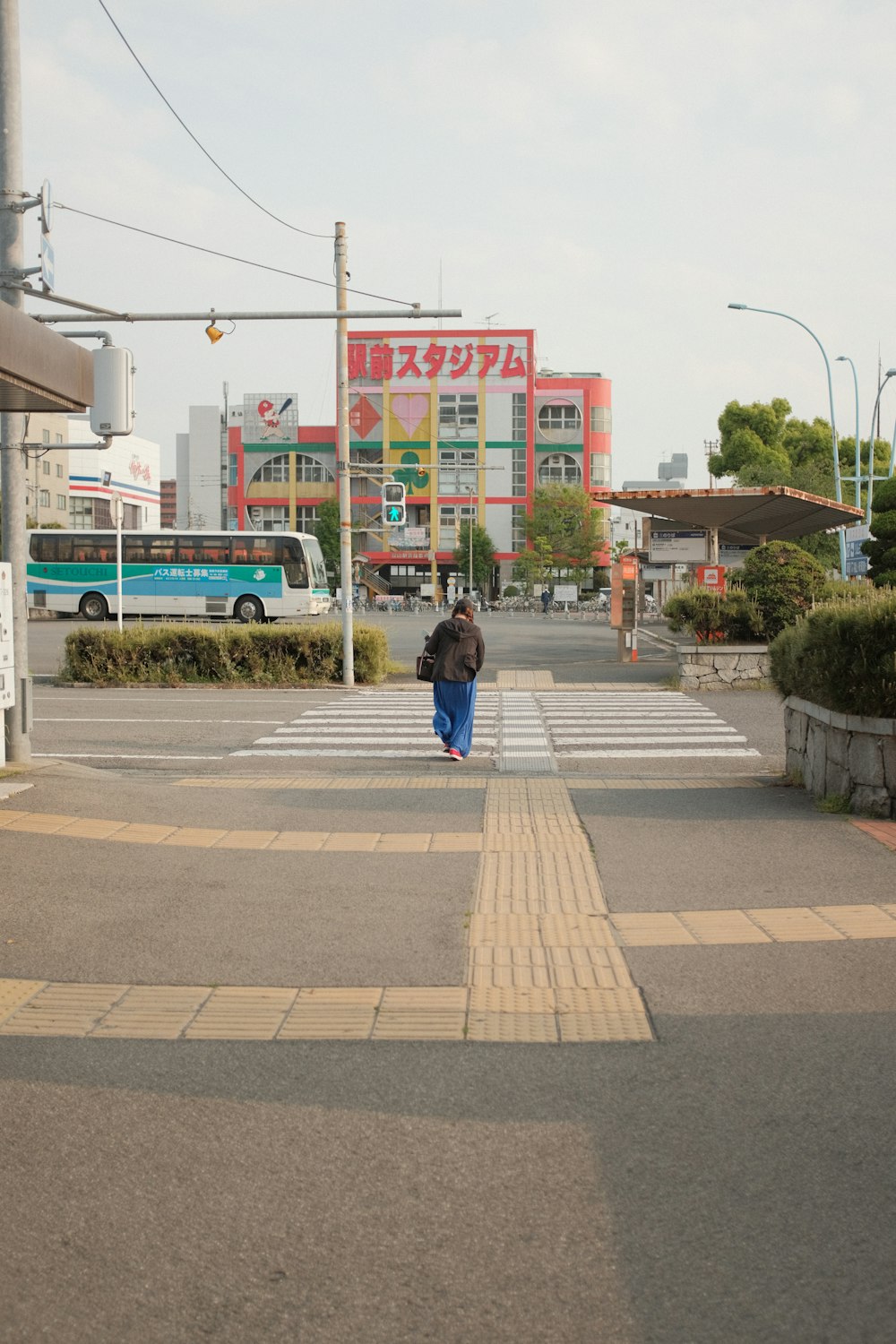 donna in giacca nera che cammina sul marciapiede durante il giorno