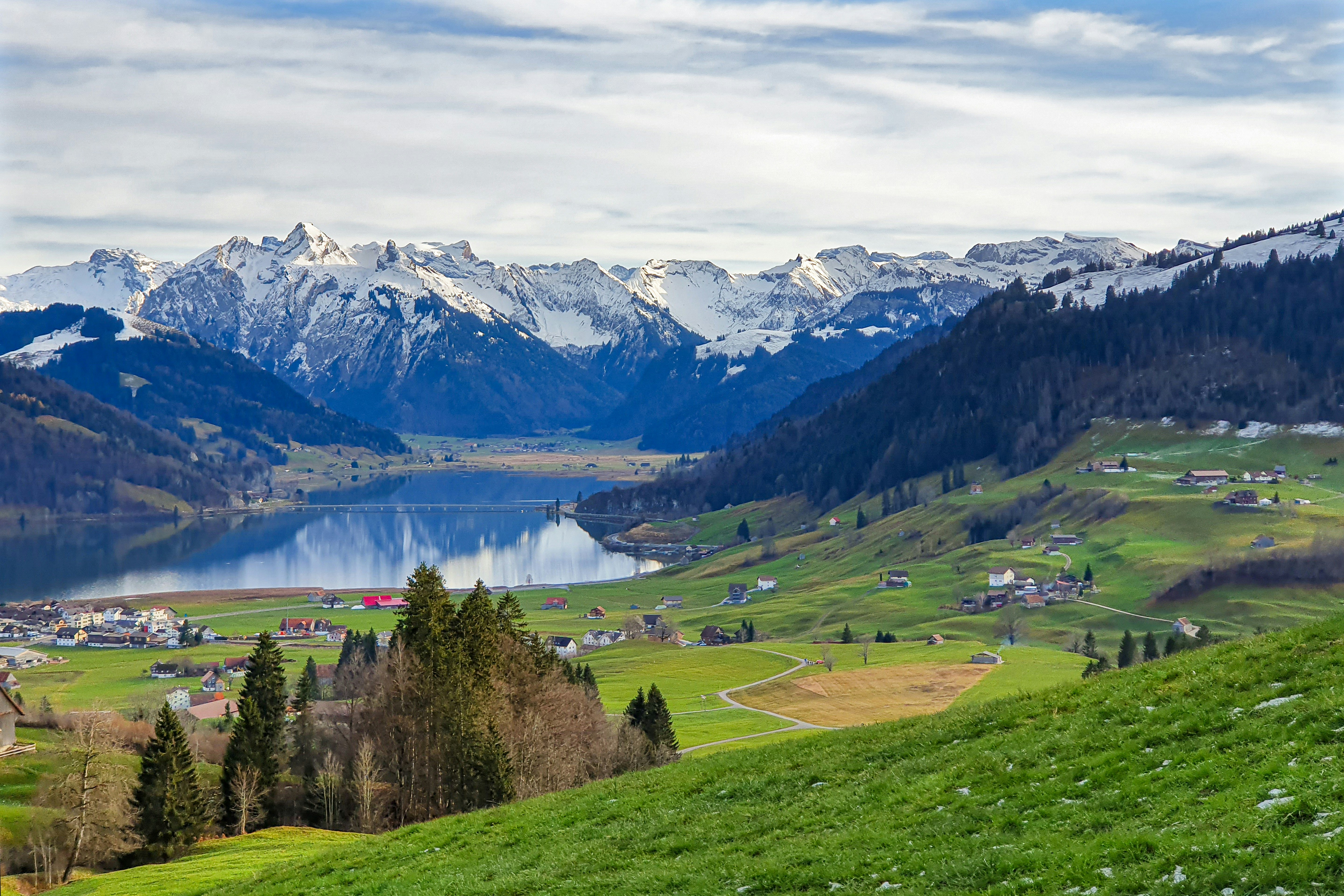 green grass field near lake under white clouds and blue sky during daytime switzerland teams background