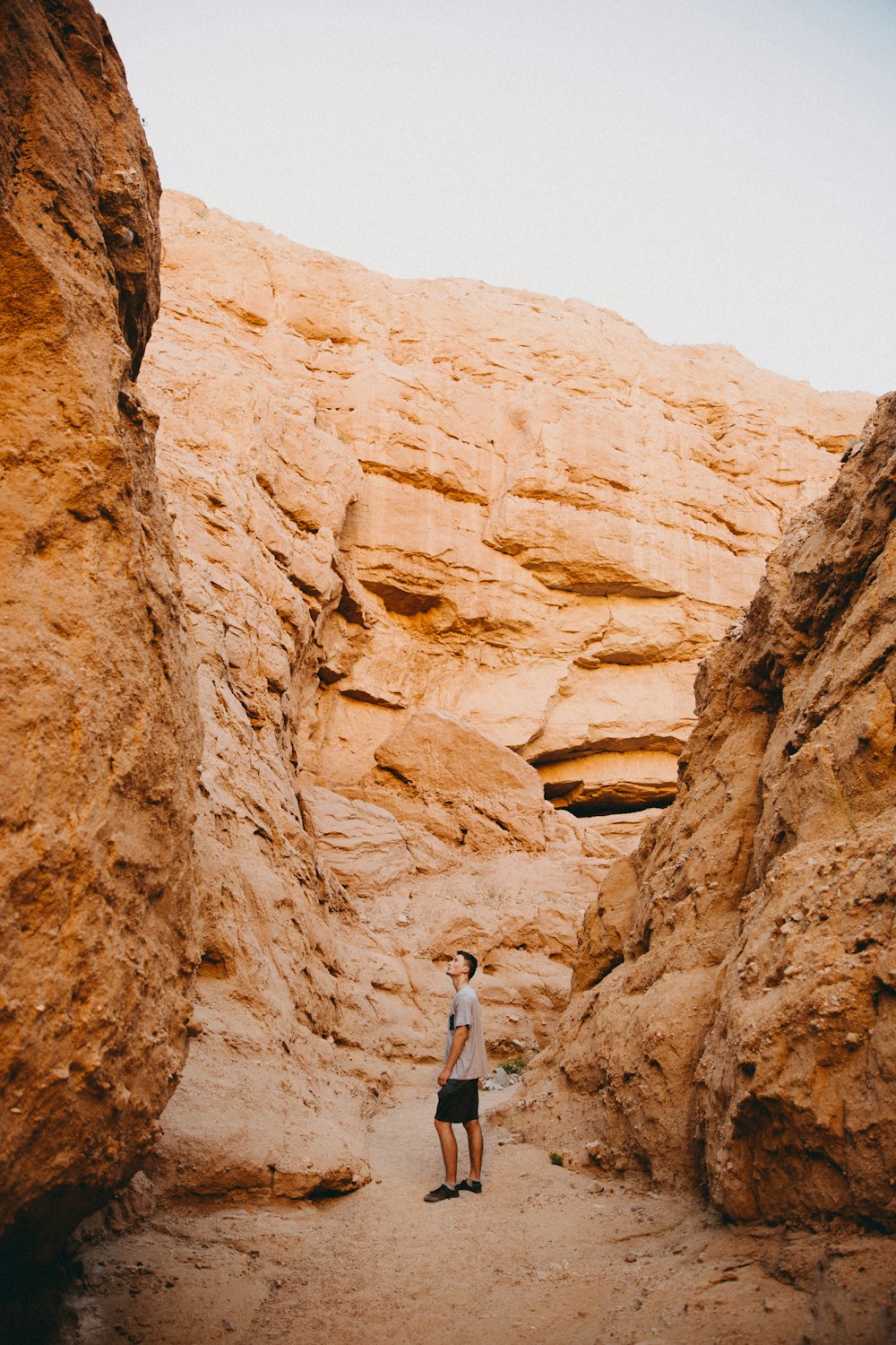 woman in blue tank top standing on brown rock formation during daytime