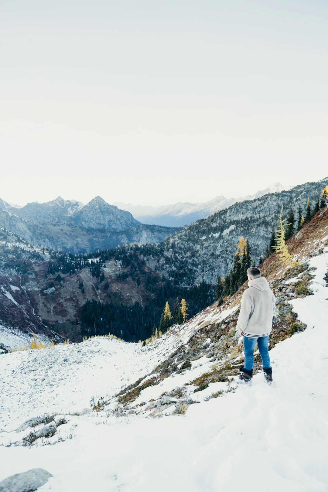 person in white jacket and blue denim jeans standing on snow covered ground during daytime