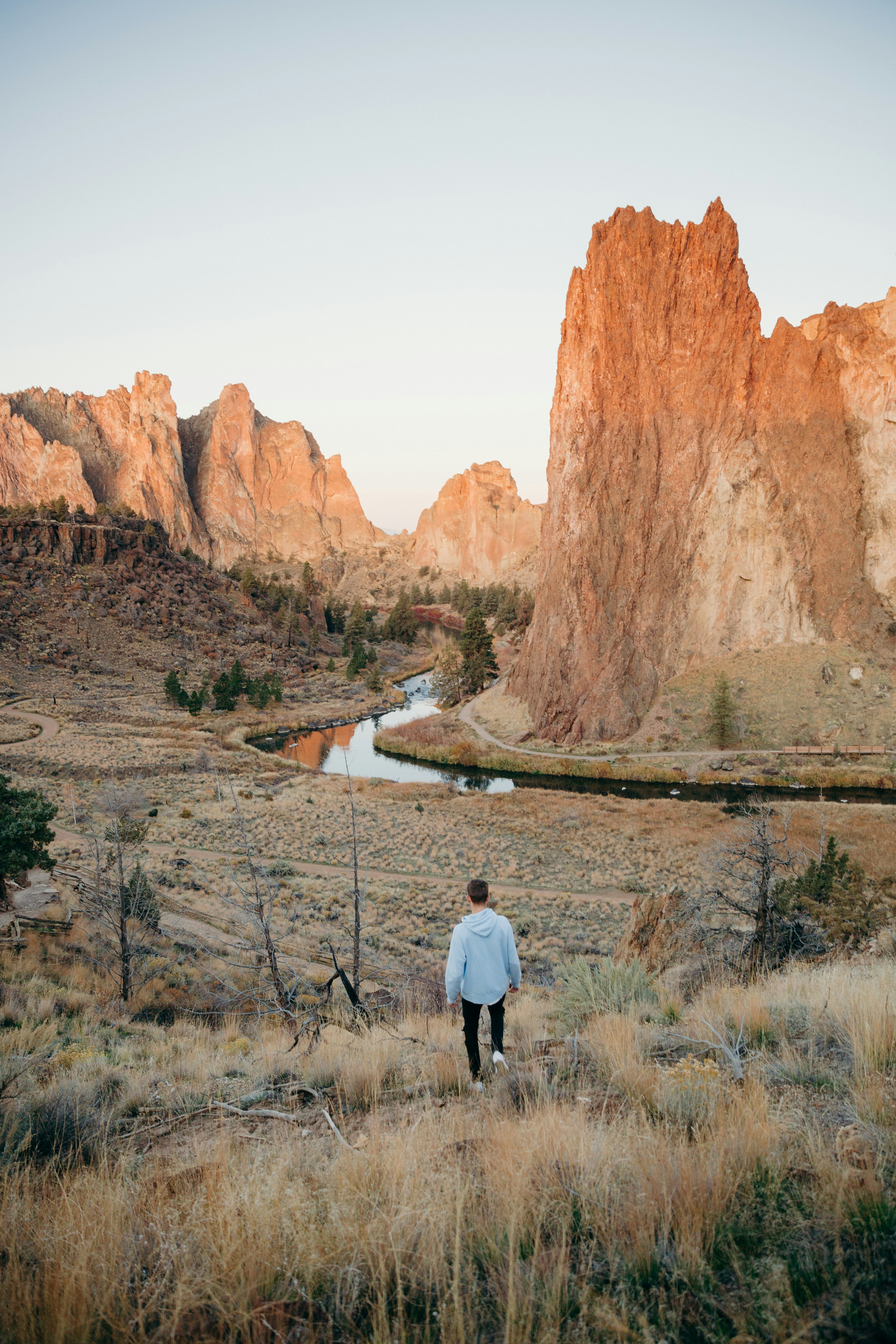 man in white long sleeve shirt standing near brown rock formation during daytime