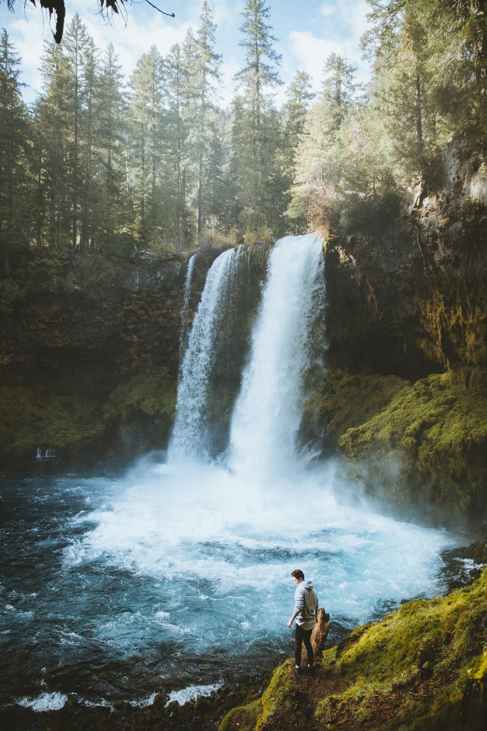 man in black shorts standing on rock near waterfalls during daytime