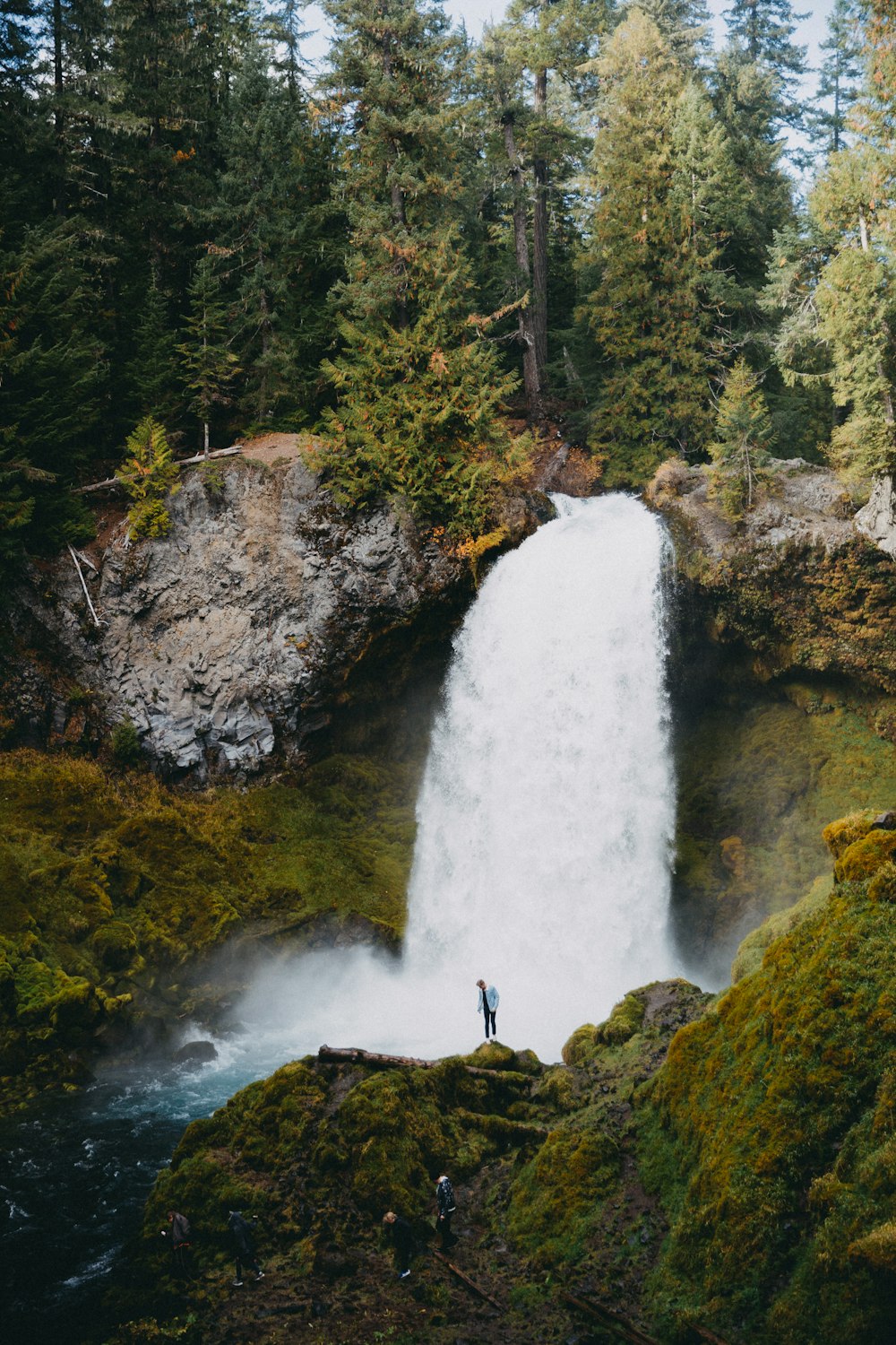 person standing on rock near waterfalls during daytime