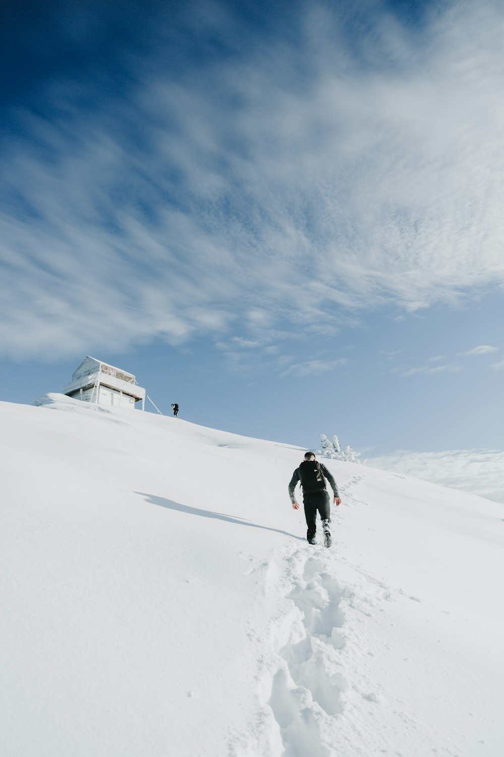 person in black jacket walking on snow covered ground under blue sky during daytime