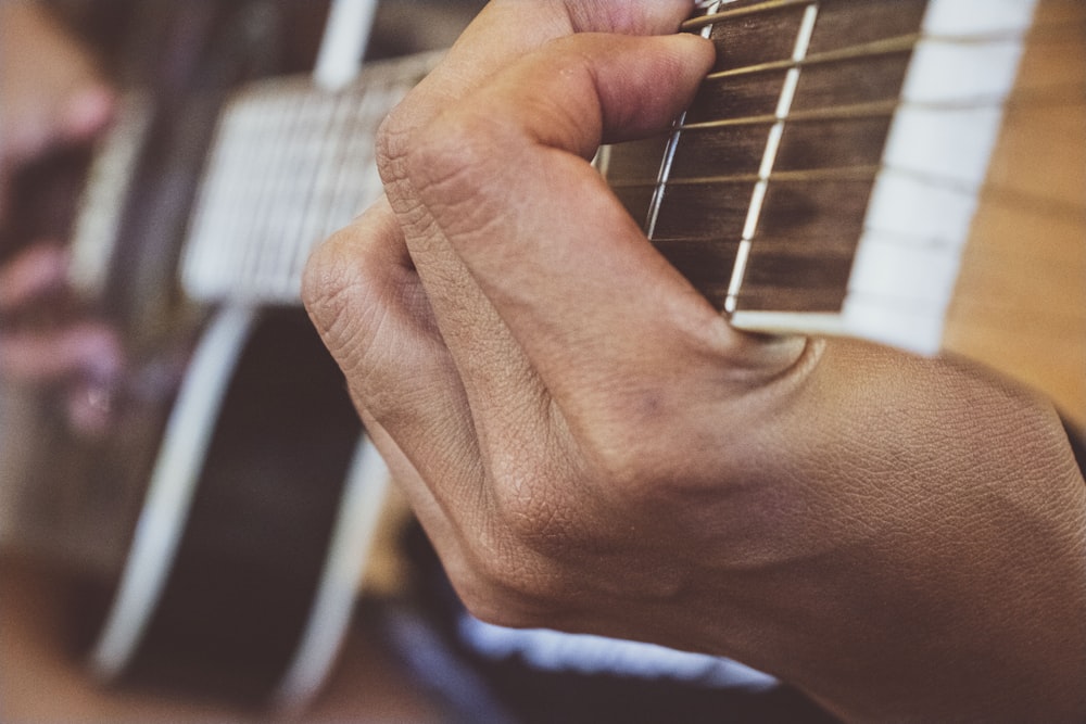 person playing guitar in grayscale photography