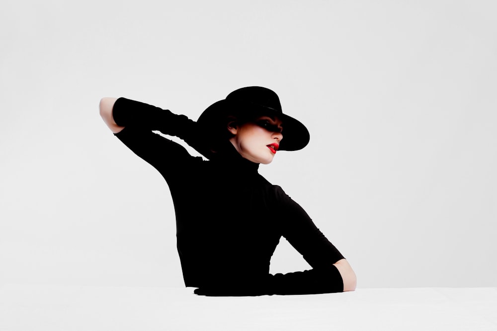 Model wearing a sculptural black hat and monochrome evening look