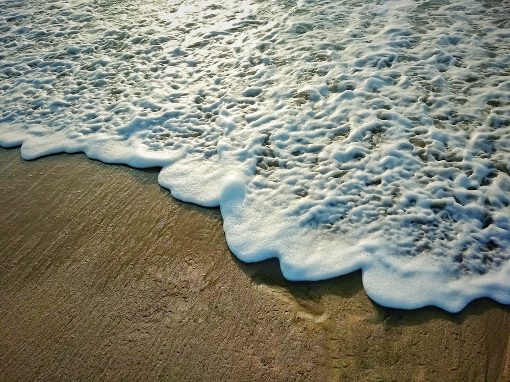 茶色の砂浜に白と青の海の波