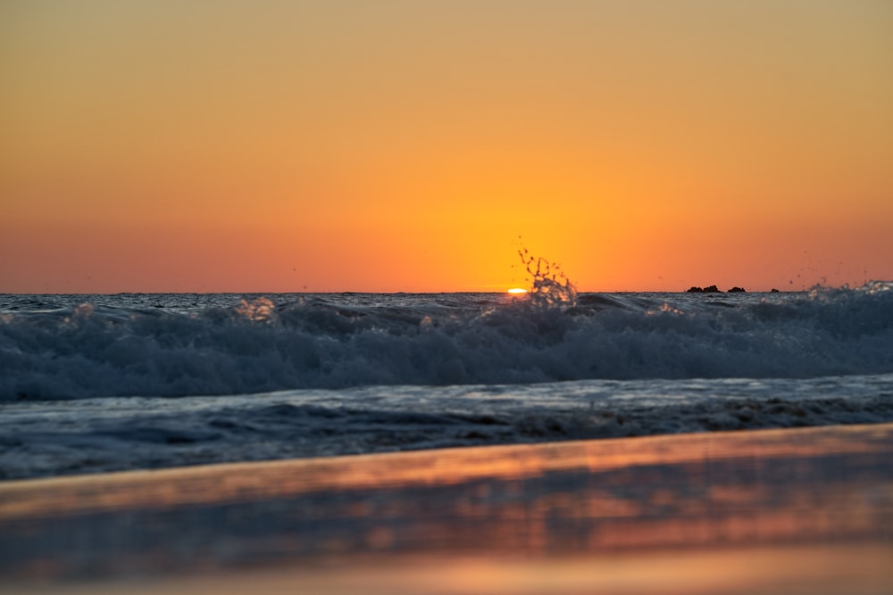 sea waves crashing on shore during sunset