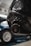 Close-up of a car's exhaust pipe with a blurred vehicle in the background, highlighting automotive components.