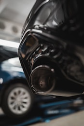 Close-up of a car's exhaust pipe with a blurred vehicle in the background, highlighting automotive components.