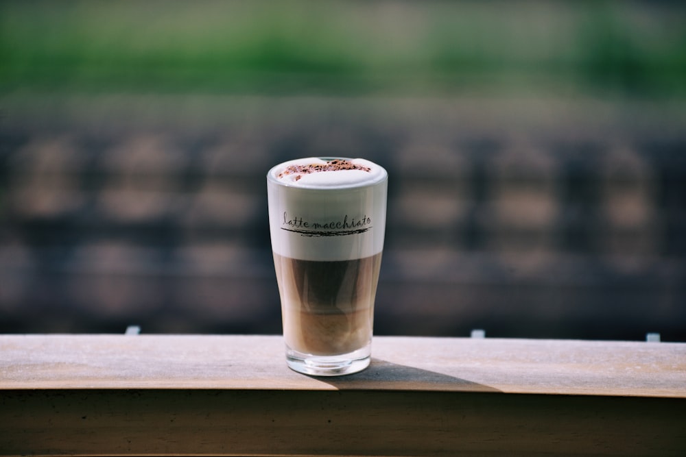 clear drinking glass with brown liquid on brown wooden table