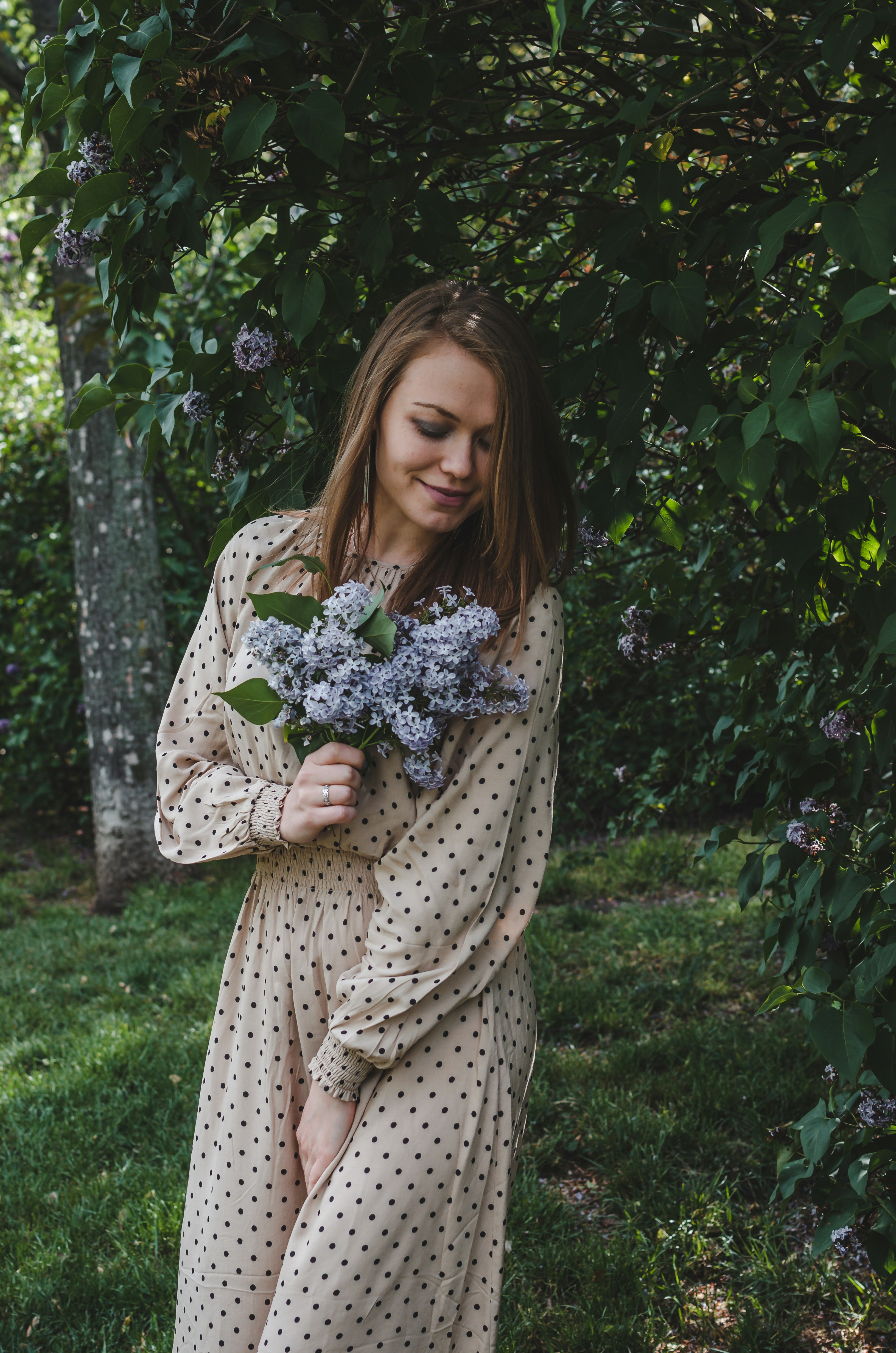 Woman in white and black polka dot dress standing on green grass field ...